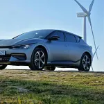 voiture électrique kia ev9 bleue garée devant éolienne