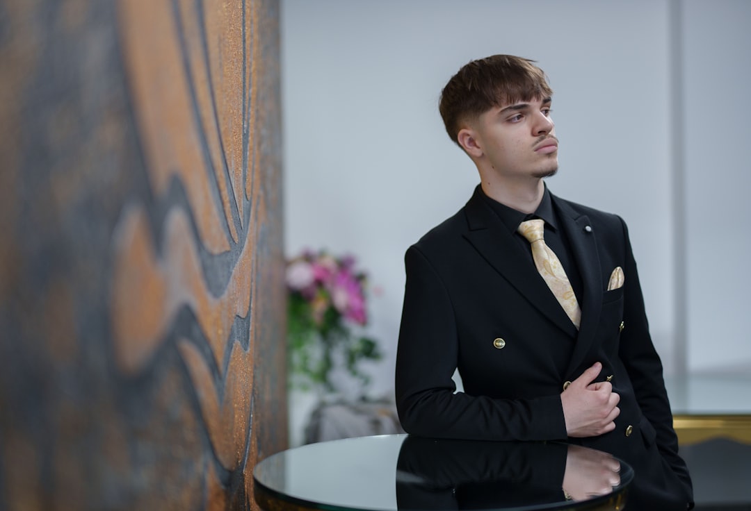 Man in a black suit with a gold tie poses.