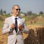 man in brown blazer and black sunglasses standing on brown grass field during daytime